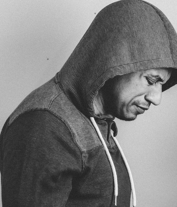 Man in a calm, focused pose in a minimalist studio with pale colors.